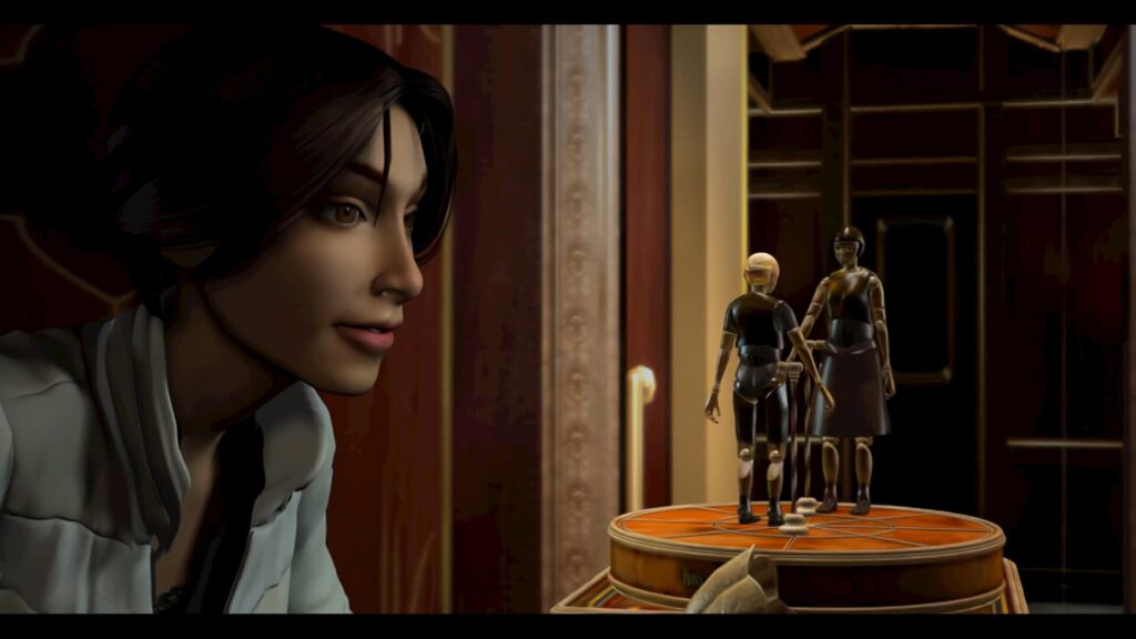 Extrait d'une cinématique de Syberia où Kate Walker regarde une boîte à musique automate où se trouvent les personnages d'Anna et Hans Voralberg