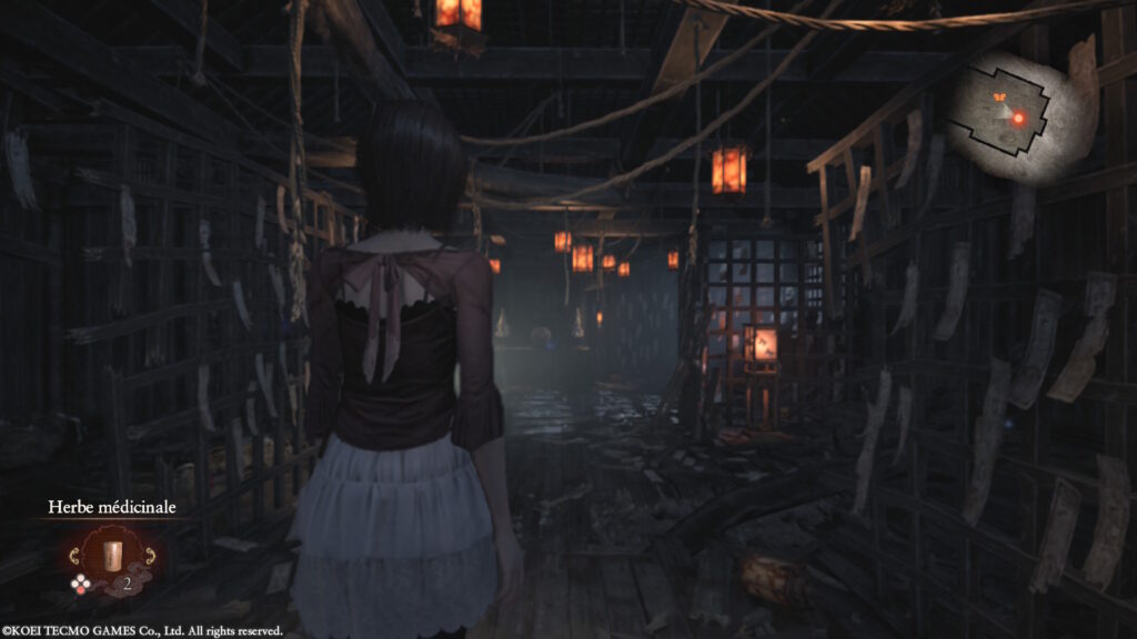 Mayu dans une maison, suivant un papillon rouge et éclairant son chemin avec une lampe torche dans Fatal Frame II
